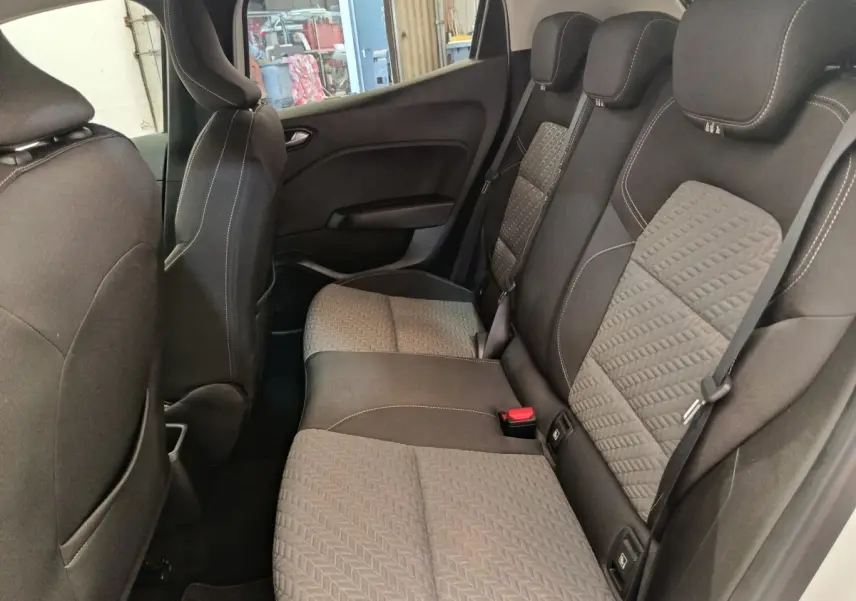 Vue intérieure côté gauche montrant la banquette arrière gris foncé avec motifs et ceintures de sécurité de la Renault Clio blanche.
