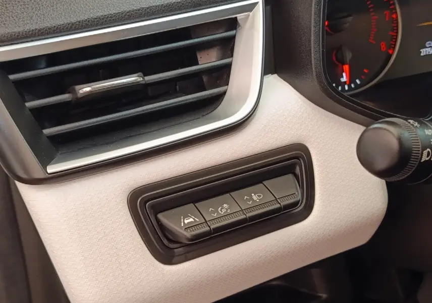 Gros plan sur les commandes d'assistance à la conduite à gauche du tableau de bord blanc de la Renault Clio Evolution TCe 100 GPL.