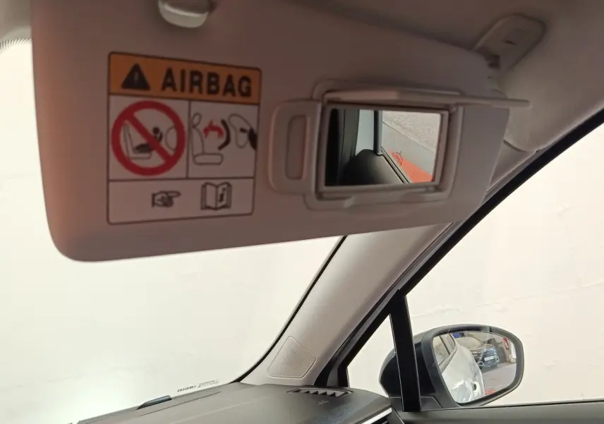Vue intérieure côté conducteur du pare-soleil blanc avec miroir et rétroviseur extérieur noir de la Renault Clio 2023.