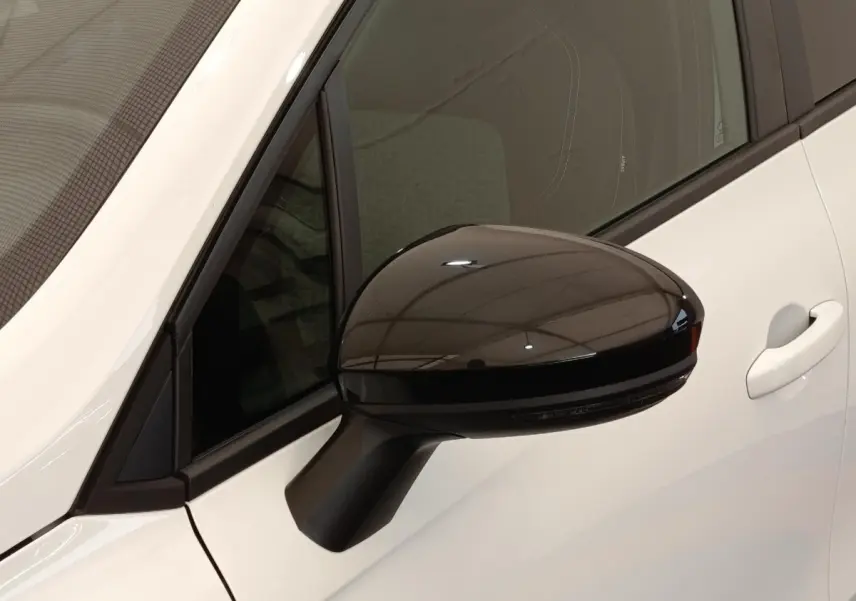 Rétroviseur droit noir brillant sur Renault Clio blanc, vue rapprochée côté avant droit avec porte visible.