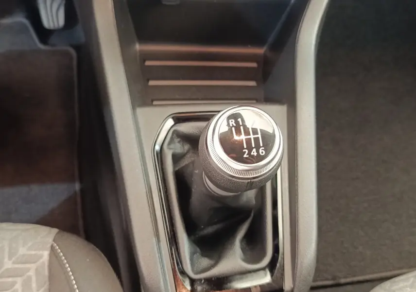 Gros plan sur le levier de vitesses manuel noir de la Renault Clio Evolution TCe 100 GPL 2023, intérieur sombre.