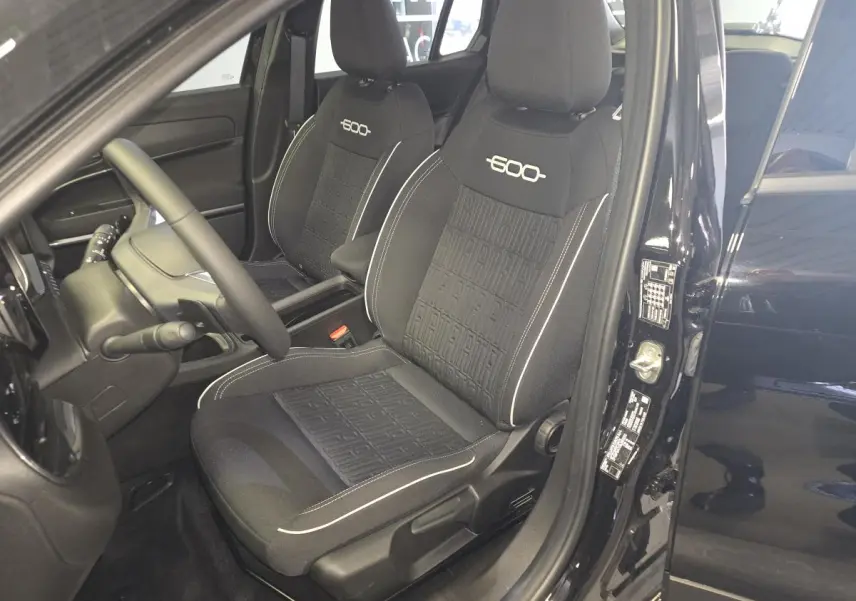 Vue intérieure côté conducteur de la FIAT 600 1.2 Hybrid noire, avec sièges spécifiques brodés et volant Soft-Touch.