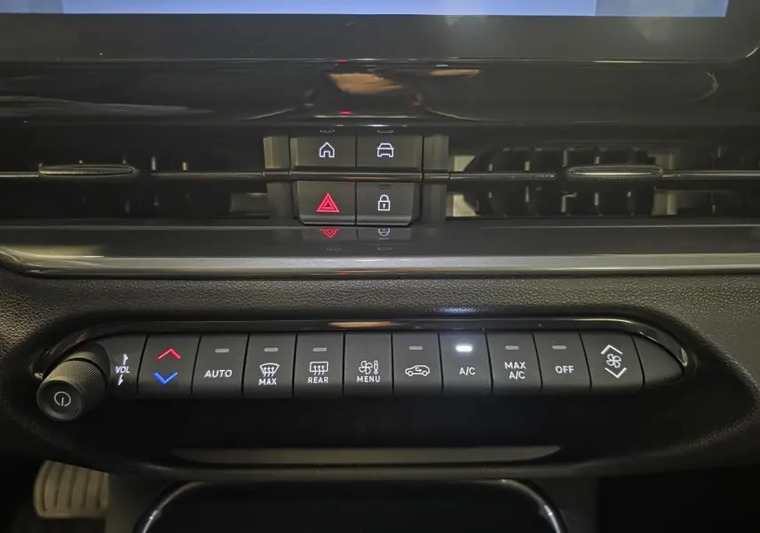 Vue rapprochée du tableau de bord noir de la Fiat 600 Hybrid 2025, montrant les commandes de climatisation et les boutons centraux.