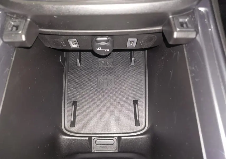 Gros plan sur la console centrale du Fiat 600 noir, montrant le chargeur smartphone par induction et deux ports USB.