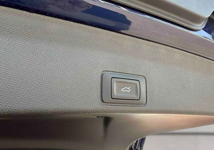 Bouton d'ouverture électrique du hayon sur la partie intérieure du coffre d'une CUPRA Terramar bleu.