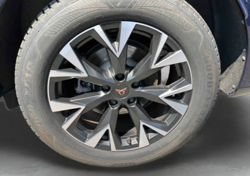 Gros plan sur la jante alliage gris anthracite à design géométrique du CUPRA Terramar bleu, avec logo CUPRA central cuivré.