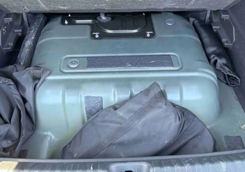 Vue du coffre ouvert de la CUPRA Terramar 2025, montrant la batterie électrique et un sac noir partiellement visible.