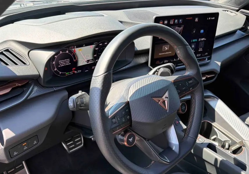 Vue intérieure du tableau de bord et volant cuir noir avec logo CUPRA cuivré, écran tactile HD et finitions texturées grises.