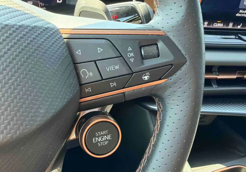 Gros plan sur le volant cuir perforé et les commandes du CUPRA Terramar 2025 avec bouton Start Engine Stop cuivré.