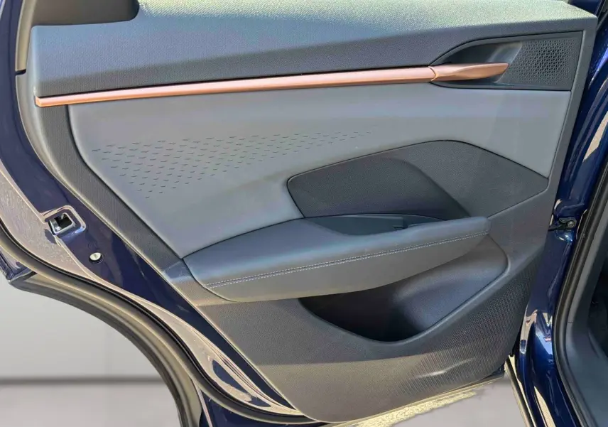 Vue rapprochée de la porte arrière gauche bleu cosmos du CUPRA Terramar avec insert cuivré et garniture noire texturée.