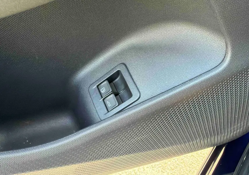 Gros plan sur la porte côté gauche de la CUPRA Terramar bleue, montrant les boutons d'ouverture du coffre et de la trappe à carburant.