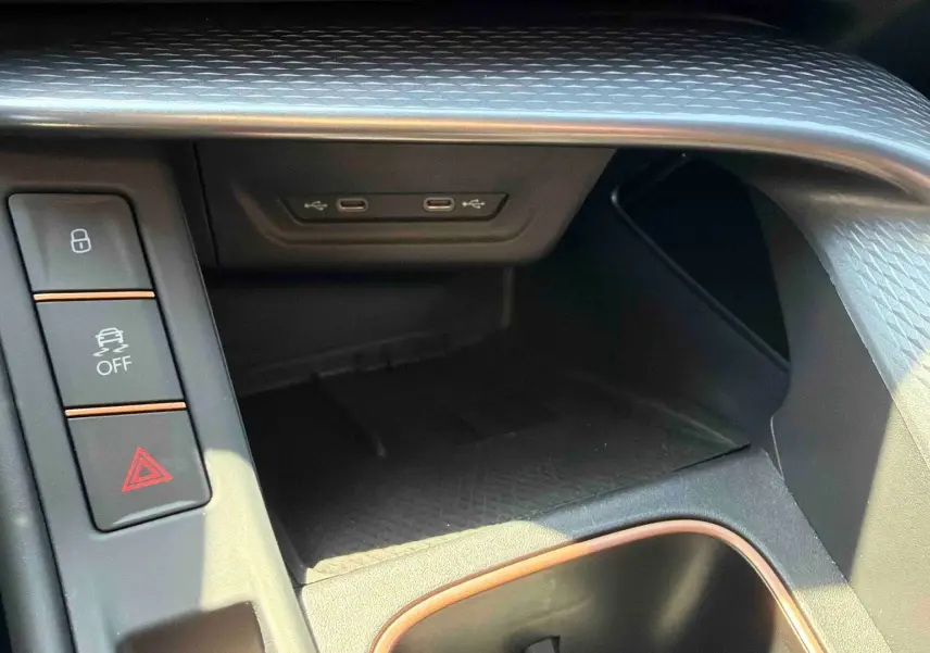 Gros plan sur la console centrale noire texturée du CUPRA Terramar avec boutons de sécurité et ports USB-C.