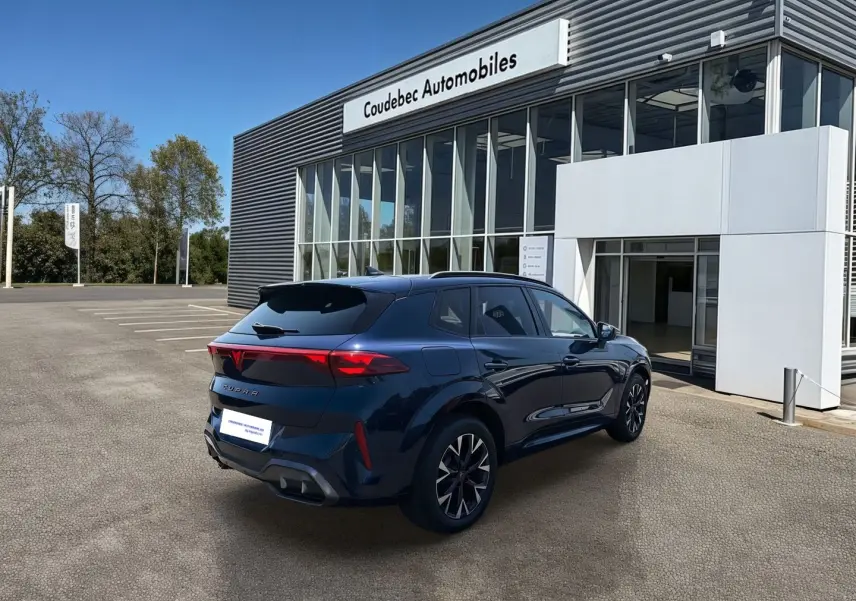 Vue 3/4 arrière droite d’un CUPRA Terramar bleu métallisé devant un bâtiment de concession Coudebec Automobiles.