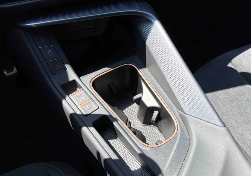 Gros plan sur la console centrale intérieure de la CUPRA Terramar bleu, avec porte-gobelets et finitions cuivrées.