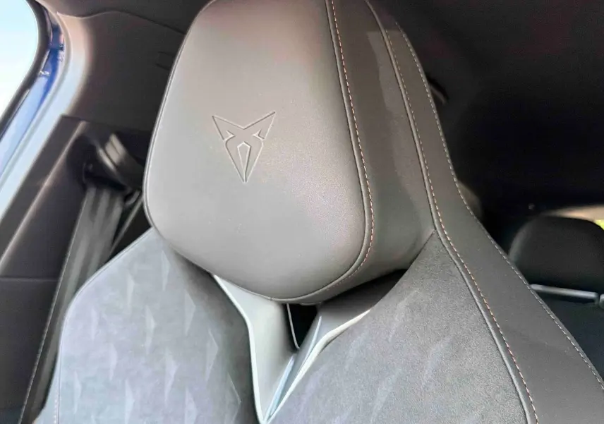 Gros plan sur l'appuie-tête avant gauche en cuir noir avec logo CUPRA embossé et surpiqûres cuivrées.
