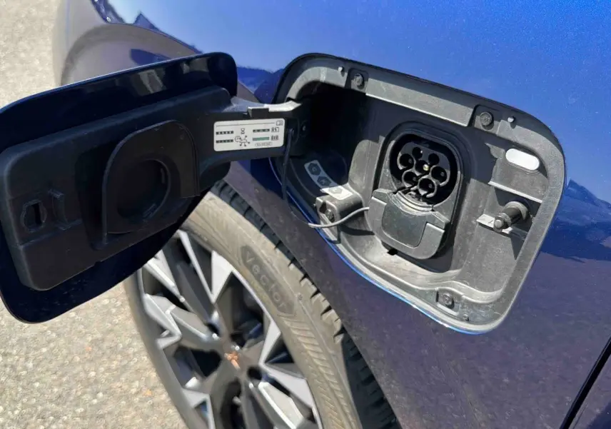 Prise de recharge électrique ouverte côté gauche sur une CUPRA Terramar bleue avec jante alliage visible.