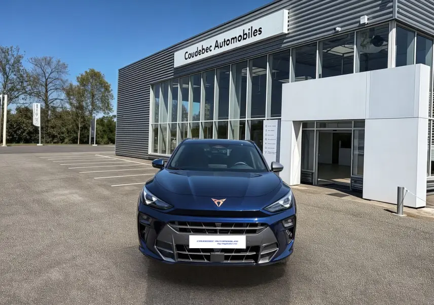 Vue avant d'une CUPRA Terramar 2025 bleu métallisé avec logo cuivré, stationnée devant un concessionnaire.