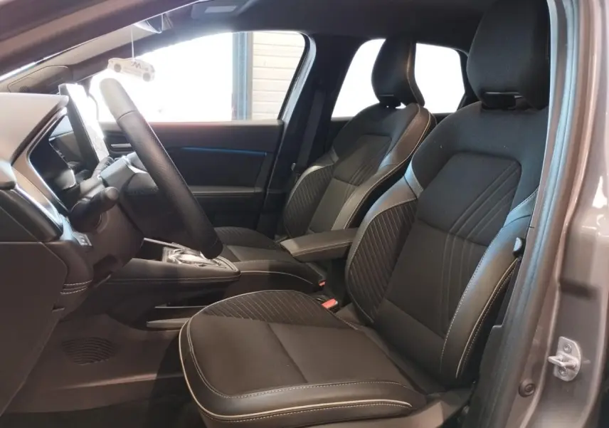 Vue intérieure côté conducteur de la Renault Symbioz 2025 gris Cassiopée, sièges noirs avec surpiqûres claires et console centrale.