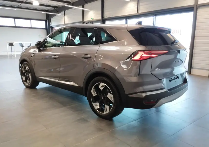 Renault Symbioz gris Cassiopée en 3/4 arrière droit, avec jantes 18 pouces et feux arrière LED allumés.