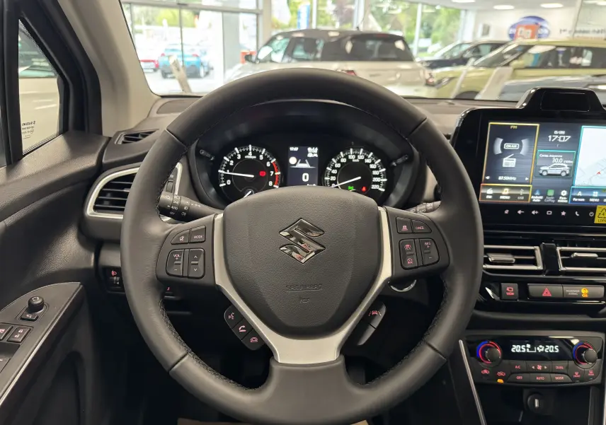 Vue intérieure centrée sur le volant noir du Suzuki S-Cross 2025 avec tableau de bord et écran tactile lumineux.