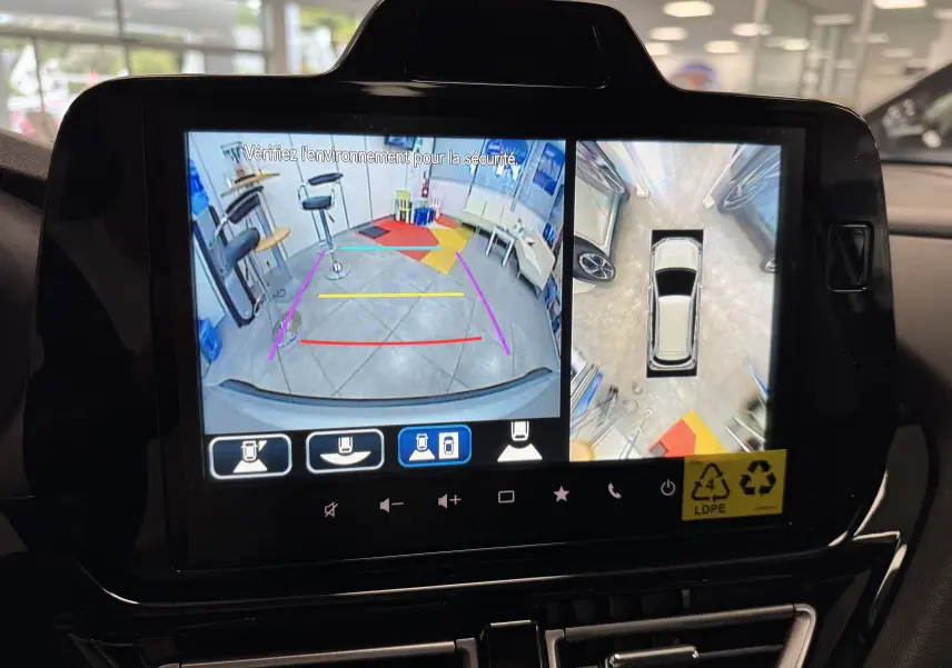 Écran multimédia montrant la caméra de recul et vue à 360° du Suzuki S-Cross gris en stationnement intérieur.