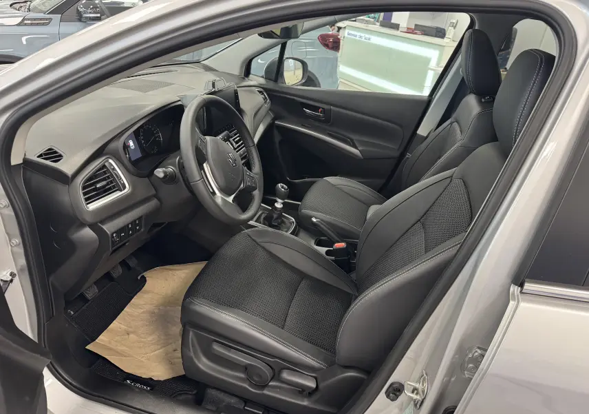 Intérieur du Suzuki S-Cross 2025 gris, vue côté conducteur, sièges noirs en cuir et tableau de bord moderne.