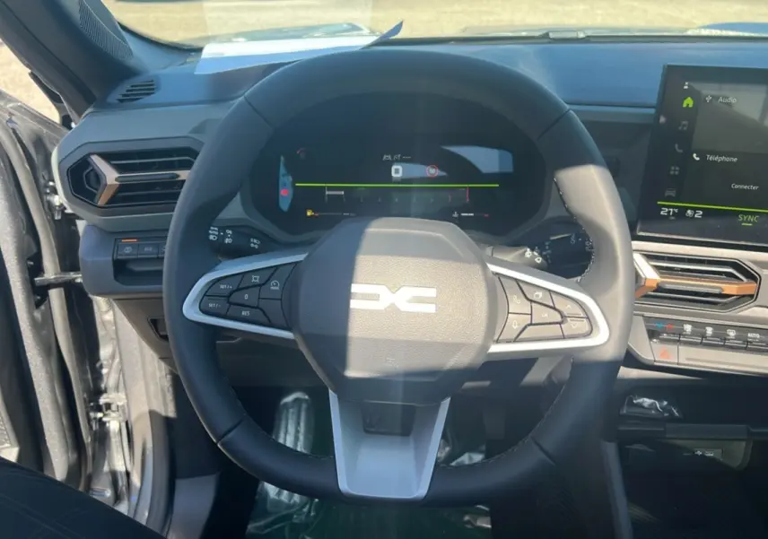 Vue intérieure centrée sur le volant du Dacia Bigster 2025 gris schiste, avec tableau de bord numérique et écran tactile.