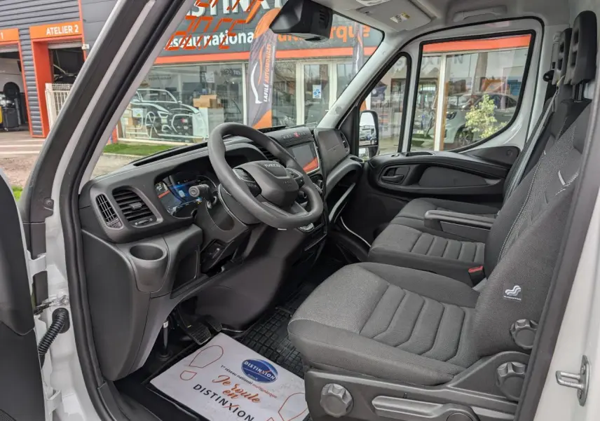 Intérieur côté conducteur du fourgon blanc Iveco Daily 35S16 2025, montrant tableau de bord et sièges gris.