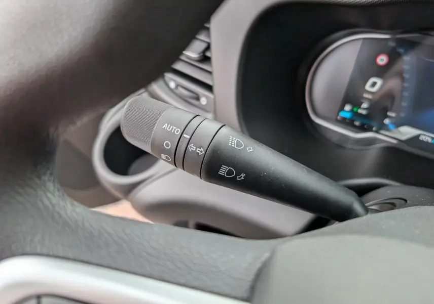 Gros plan sur la commande d'éclairage automatique à gauche du volant dans l'habitacle du Iveco Daily blanc.