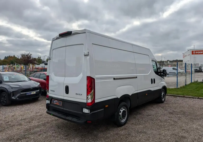 Vue 3/4 arrière droite d’un utilitaire Iveco Daily blanc avec portes arrière battantes et marchepied noir.