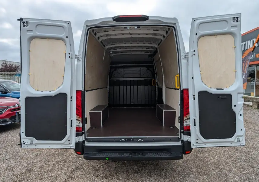 Vue arrière du fourgon blanc Iveco Daily 35S16 avec portes ouvertes et intérieur de chargement aménagé en bois.