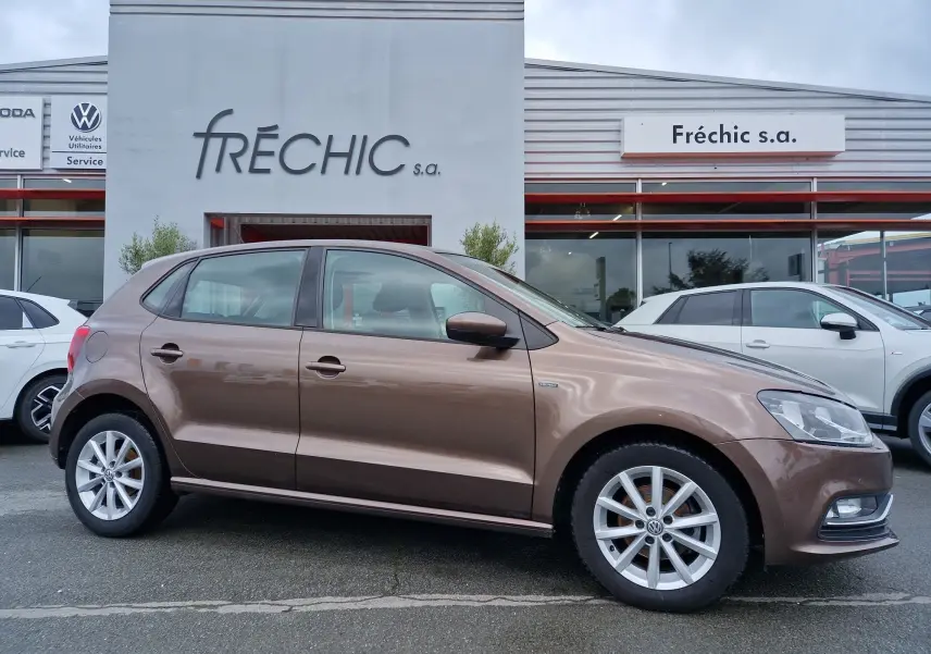 Vue de profil côté gauche d'une Volkswagen Polo 1.4 TDI 2015 brun métallisé stationnée devant un garage.