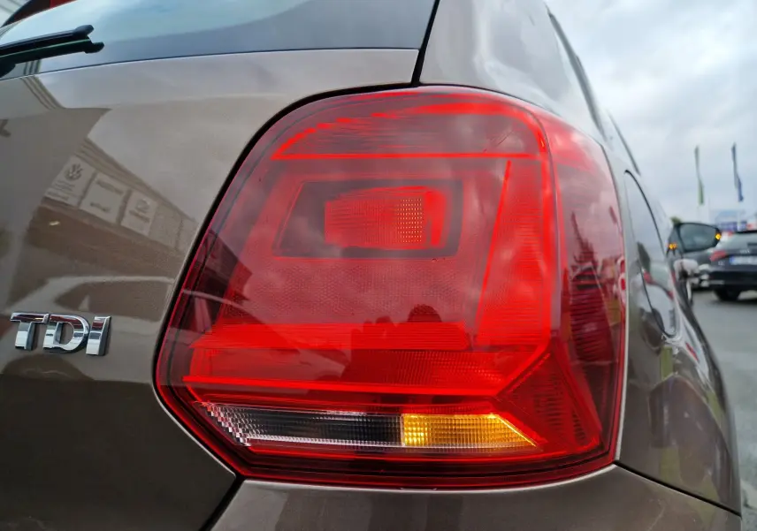 Gros plan sur le feu arrière droit d'une Volkswagen Polo 1.4 TDI brun 2015 avec logo TDI visible sur la carrosserie.
