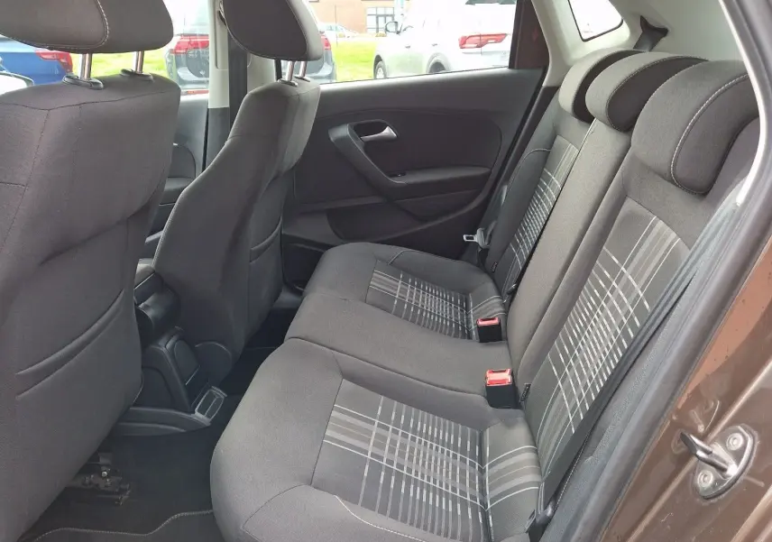 Vue intérieure côté droit des sièges arrière en tissu gris à motifs de la Volkswagen Polo 1.4 TDI brun 2015, porte ouverte.