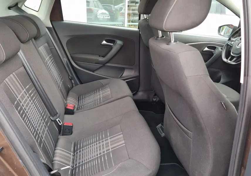 Vue intérieure côté gauche arrière de la Volkswagen Polo 1.4 TDI 2015 brun, montrant les sièges tissu à motifs et l'habitacle spacieux.