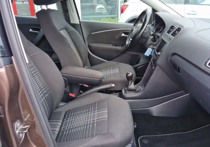 Vue intérieure côté conducteur d'une Volkswagen Polo 2015 brun 4Q4Q, finition Lounge avec sièges tissu à motifs et boîte manuelle.