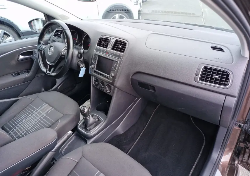 Vue intérieure côté conducteur de la Volkswagen Polo 1.4 TDI brun, montrant le tableau de bord et la boîte manuelle.