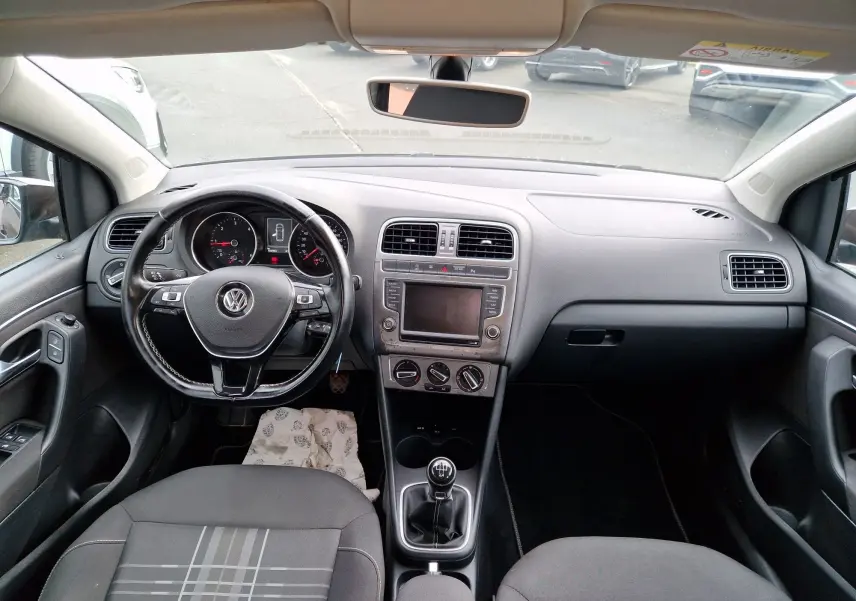 Vue intérieure avant du tableau de bord d'une Volkswagen Polo 1.4 TDI 2015 finition Lounge, avec volant cuir multifonction et levier de vitesse manuel.