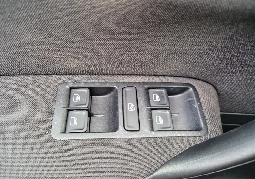 Gros plan sur les commandes de lève-vitres électriques sur la porte intérieure d'une Volkswagen Polo 1.4 TDI 2015 finition Lounge.