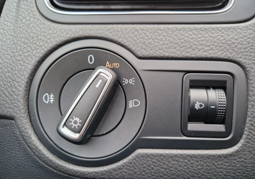 Gros plan sur le bouton de commande des phares et réglage de l’éclairage intérieur d’une Volkswagen Polo 2015 finition Lounge.