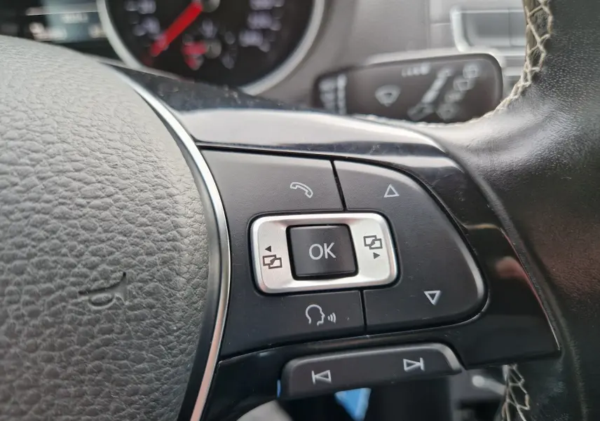 Gros plan sur les commandes multifonctions à droite du volant en cuir noir de la Volkswagen Polo 2015 finition Lounge.