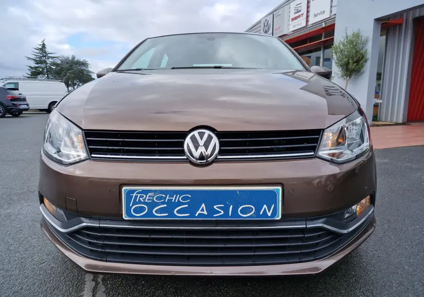 Vue frontale d'une Volkswagen Polo 1.4 TDI brun 2015 avec calandre noire et plaque d'immatriculation bleue "Fréchic Occasion".