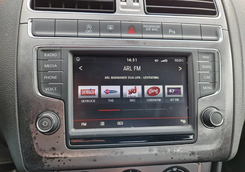 Vue rapprochée de l’écran multimédia central de la Volkswagen Polo 1.4 TDI 2015 avec interface radio et boutons de commande.