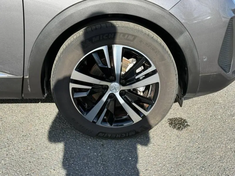 Gros plan sur la roue avant gauche du Peugeot 3008 Gris Platinium 2024 avec jante alliage noire et argentée.