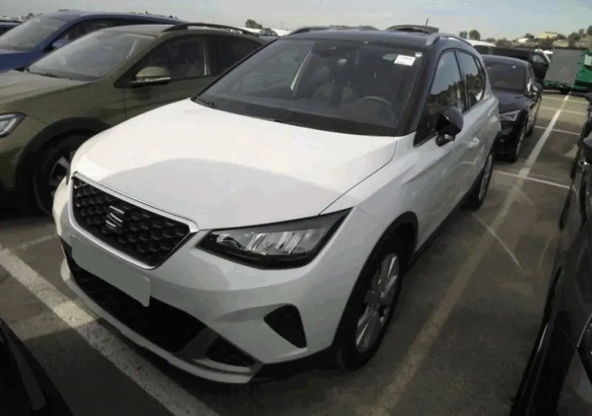 SEAT Arona blanc Nevada en 3/4 avant droit, avec calandre noire et toit noir contrasté visible.