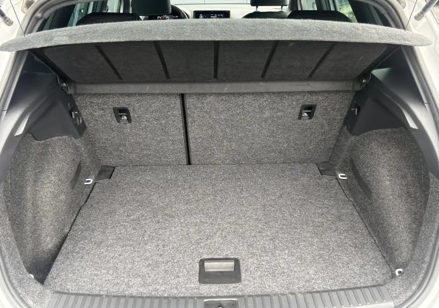 Coffre ouvert vu de l'arrière d'un SEAT Arona blanc Nevada, montrant un espace de chargement propre et spacieux.