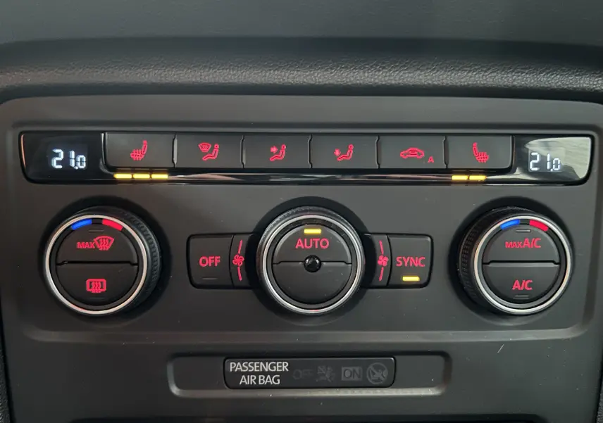 Gros plan sur la console de climatisation de la Volkswagen Coccinelle gris, affichant 21°C avec commandes chauffantes et ventilation.