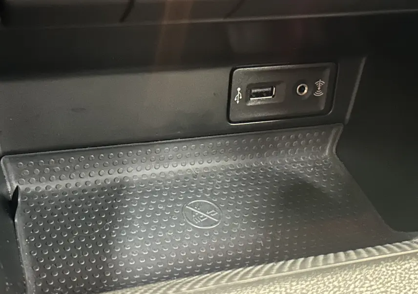 Gros plan sur la console centrale de la Volkswagen Coccinelle 2016 montrant une prise USB et une entrée auxiliaire.