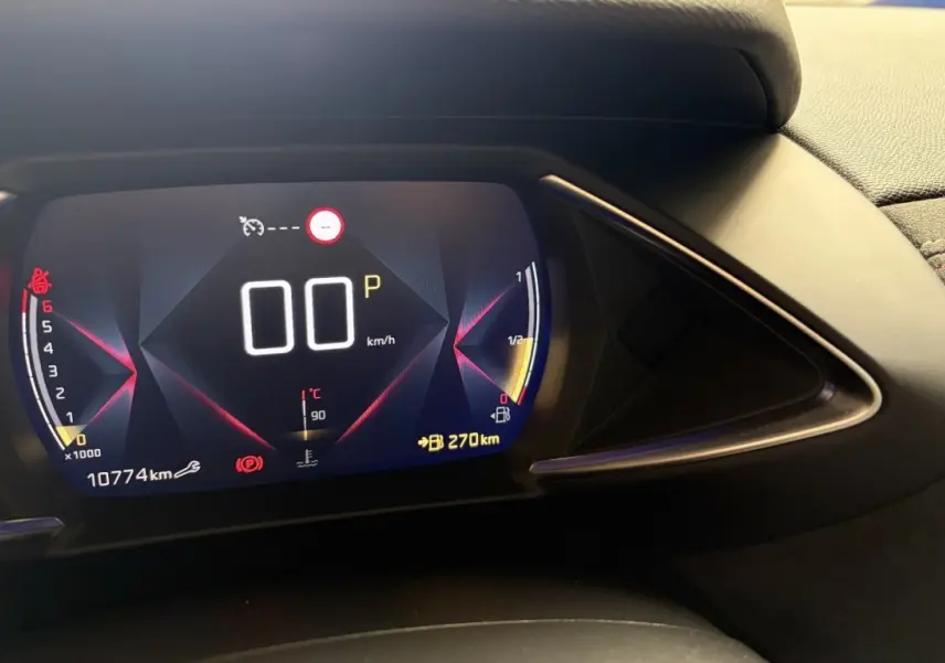 Gros plan sur le tableau de bord numérique du DS3 Crossback blanc, affichant la vitesse, le régime et l'autonomie.