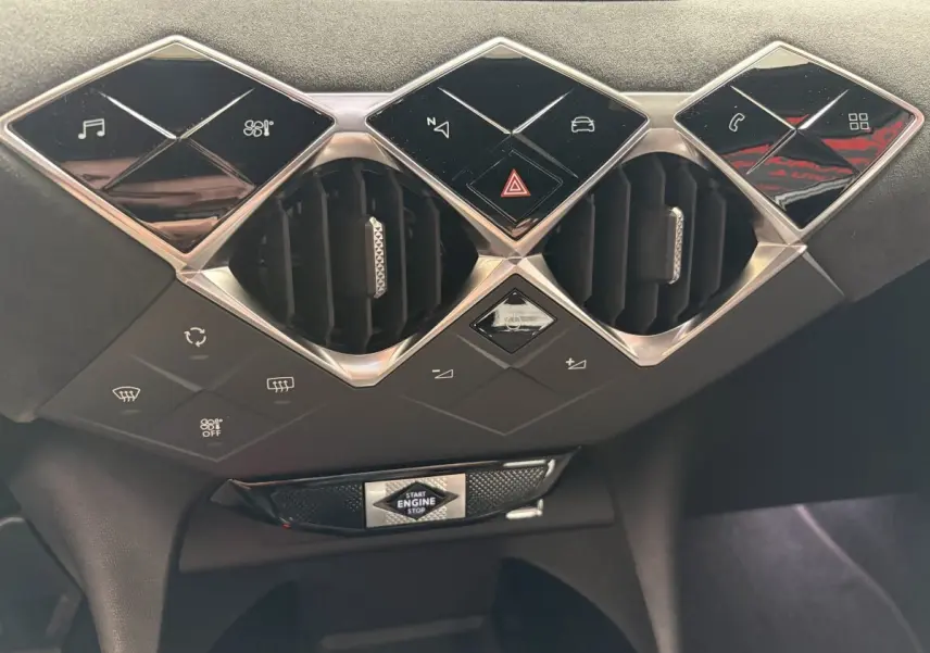 Vue rapprochée du tableau de bord central du DS3 Crossback blanc, avec commandes tactiles et bouton start/stop.
